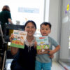 Mother and son duo smile as they hold up with children's books.