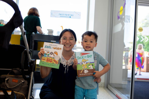 Mother and son duo smile as they hold up with children's books.