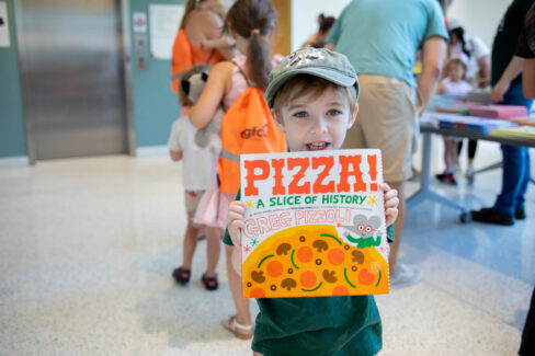 Child patron happily holds up a children's book.