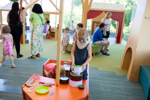 Girl with a face painting of a butterfly is seen playing with toys in the children's room.