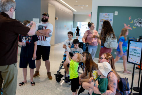 Families stand in the lobby of the library, with faces of excitement.