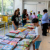 Librarians assist families pick children's books from a table.