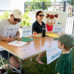Little kid stands as author autographs a children's book.